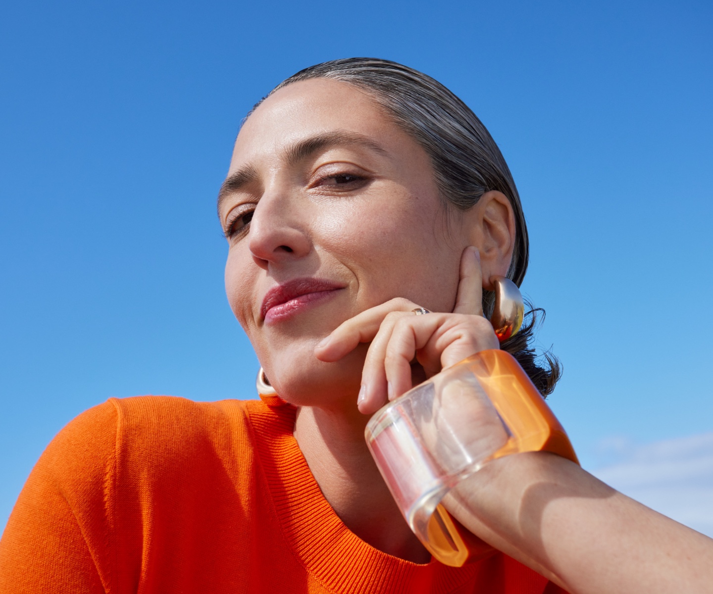 Close-up of woman's face with makeup in orange shirt