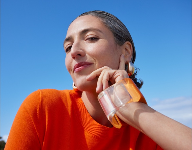 Woman in an orange top promoting skincare products
